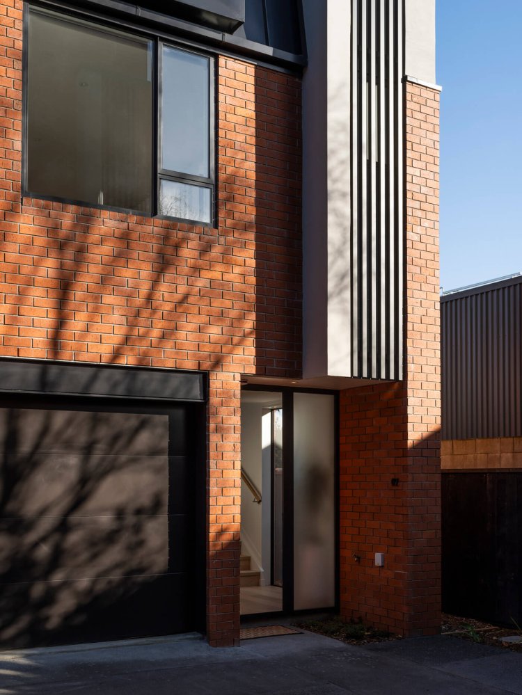 Exterior of Mesa Morningside Auckland townhouses garage and entrance crafted in industrial looking clay brick and black metal